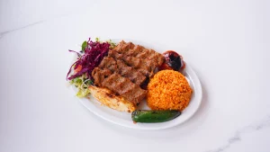 QR Menu Spicy minced meat Adana kebab served with bulgur pilaf and grilled vegetables.